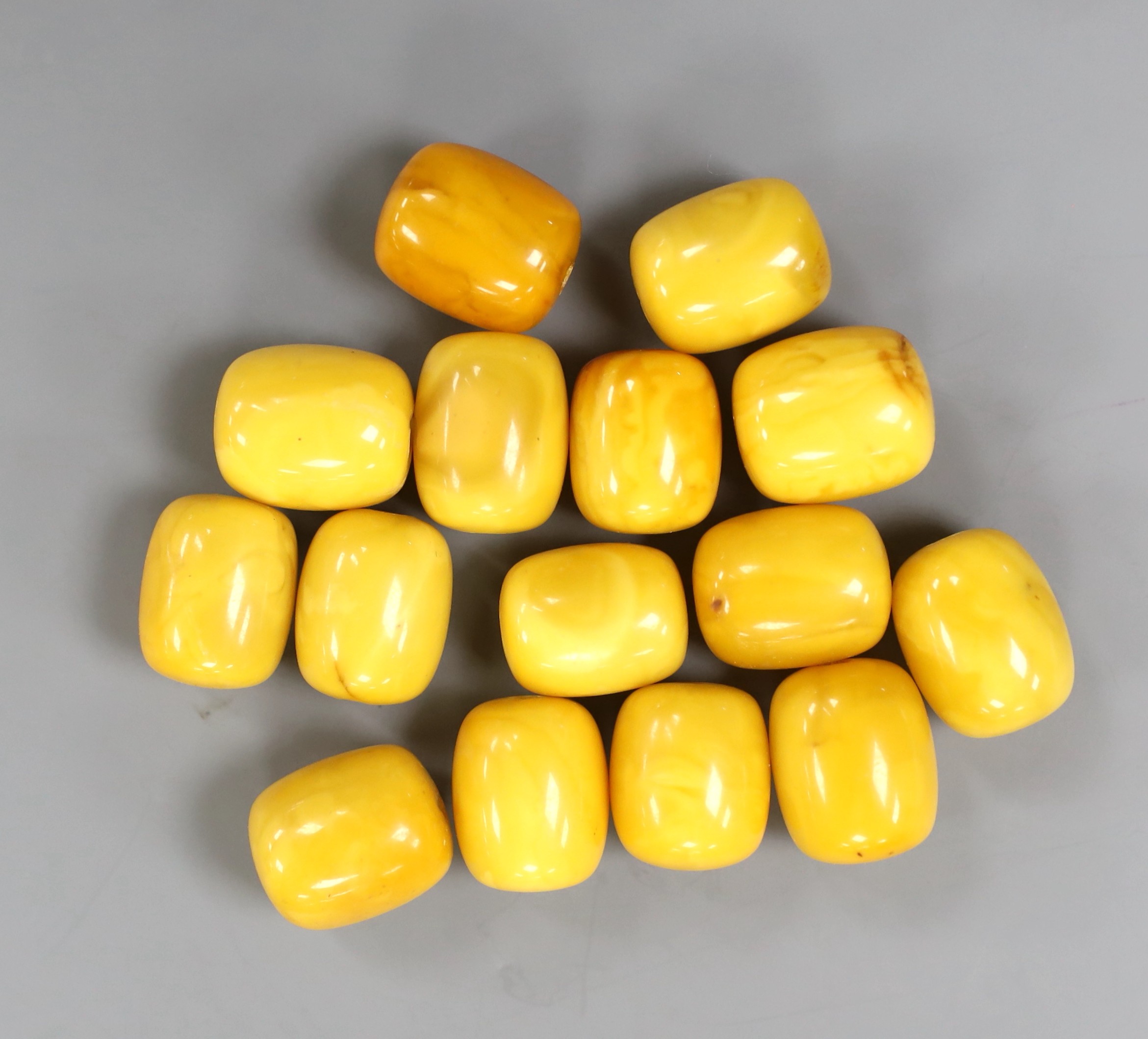 A group of fifteen loose drilled amber beads, 46 grams.